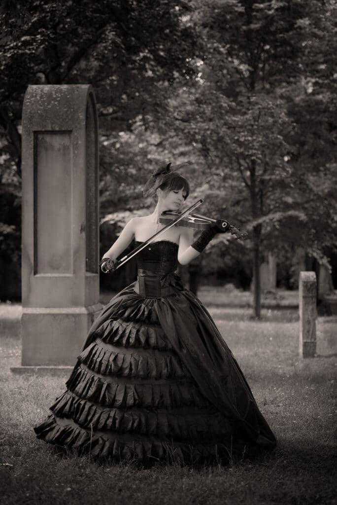 Beauty & Fashion Aufnahme - junge Frau in einem schwarzen Kleid spielt Geige