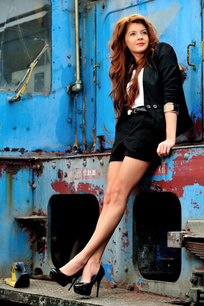 Beauty & Fashion Aufnahme - junge Frauim kurzen Businessjostüm auf high heels auf einer Lokomotive