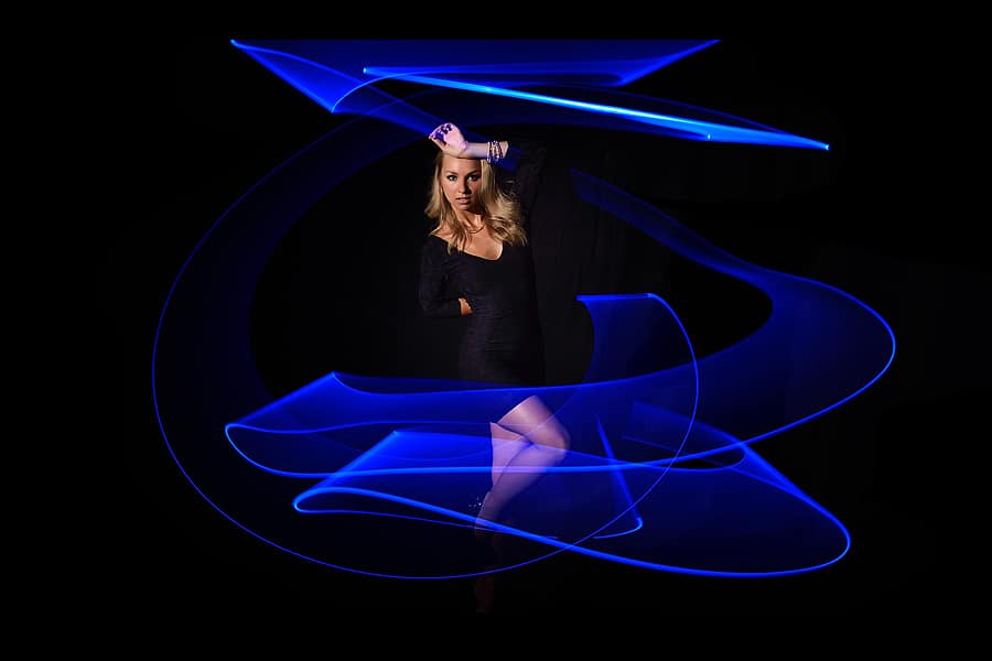 Blue Light Painting - Modell im Studio vor schwarzem Hintergrund und mit blauer Lichtspur um das Modell herum