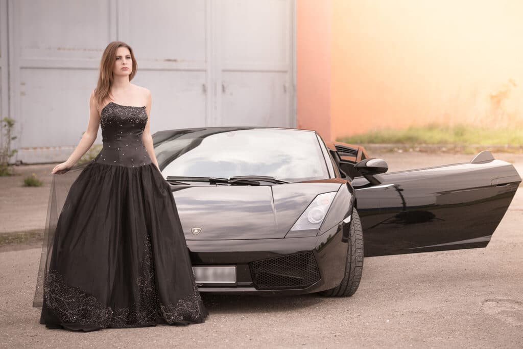 Lady in Black mit Stier - Junge Frau im schwarzem Abendkleid vor einem Lamborghini Gallardo und ein großes Hallentor im Hintergrund